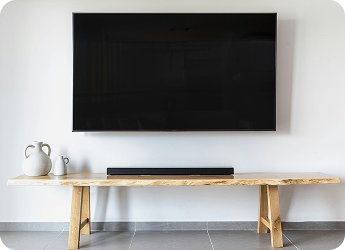 New television mounted on wall above a wooden table.