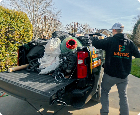 EasyGig Junk Removal hauler loading up a pickup truck in a Charlotte, NC neighborhood.