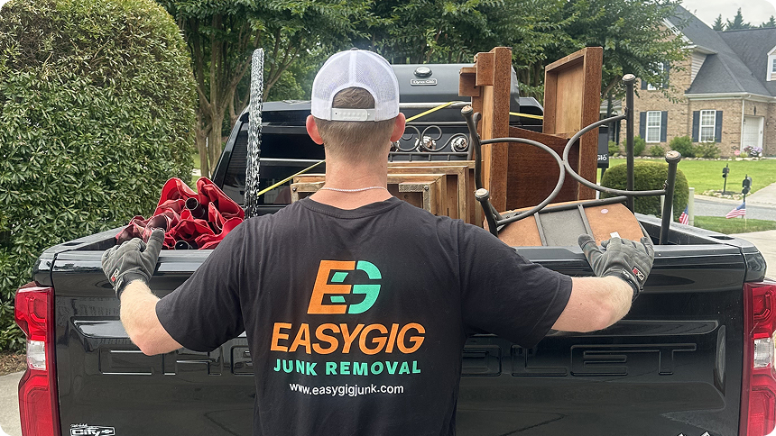EasyGig Junk Removal hauler loading furniture and household items into a pickup truck.