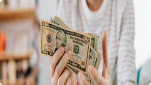 Gig worker holding cash earnings, comparing junk hauling pay vs side gigs like delivery and rideshare