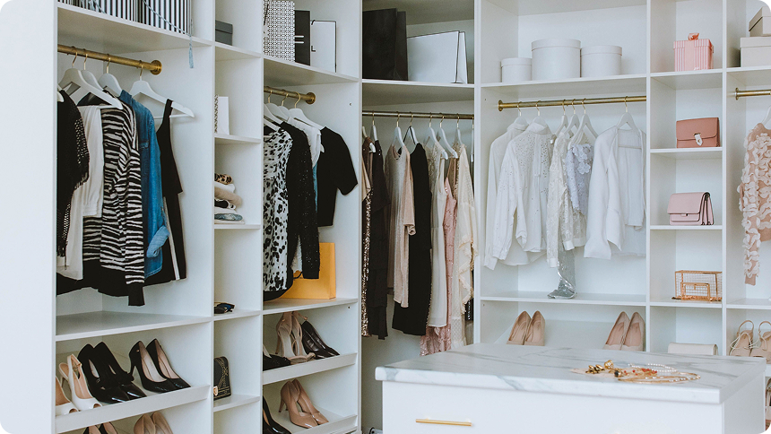 Beautifully organized walk-in closet with color-coordinated clothing, shoes, and accessories neatly arranged on shelves