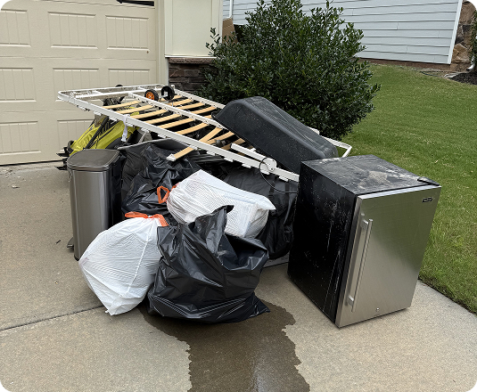 Discarded furniture, appliances, and trash bags piled at the curb during a home organizing cleanout