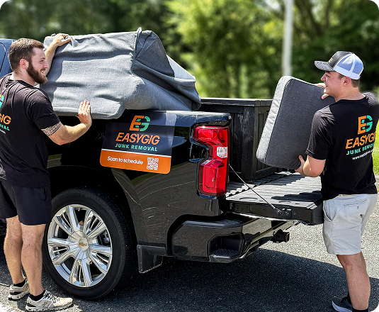 Two EasyGig Junk Removal Haulers having fun while loading up a pickup truck.
