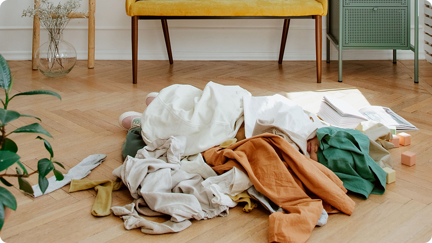 A person under a pile of clothes after decluttering